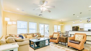 A spacious living room with a sofa, coffee table, and two armchairs. A ceiling fan and pendant lights are visible. - Dog Friendly, Private Beachside Home in Pirates Beach w/ Covered Deck (Galveston)