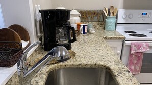 Une cuisine équipée d’un évier en acier inoxydable à deux bacs, d’une machine à café et d’une cuisinière.