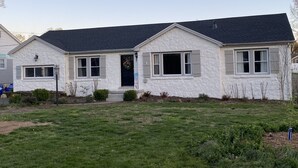 Une maison de plain-pied avec une façade en pierre, un toit sombre et une porte d’entrée ornée d’une guirlande.