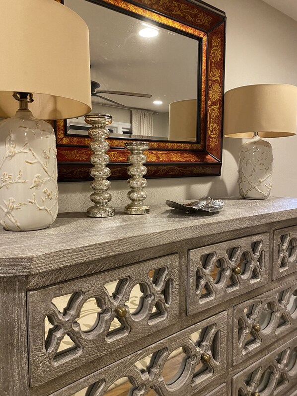 A wooden dresser with intricate carvings and two lamps with floral designs.