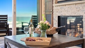 A wooden table with a glass vase of flowers, a bottle of wine, and a tray of snacks. - Cielo Mar | 4BR Oceanfront Escape + Rooftop (San Diego)