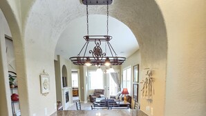 A kitchen with a granite countertop, wooden cabinets, and a hanging chandelier.