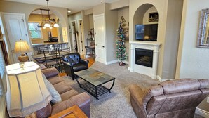 A living room with a fireplace, a dining area with a chandelier, and a Christmas tree.