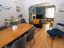 Una sala de estar moderna con una mesa de comedor de madera, sillas tapizadas en gris, un sofá azul y una chimenea.