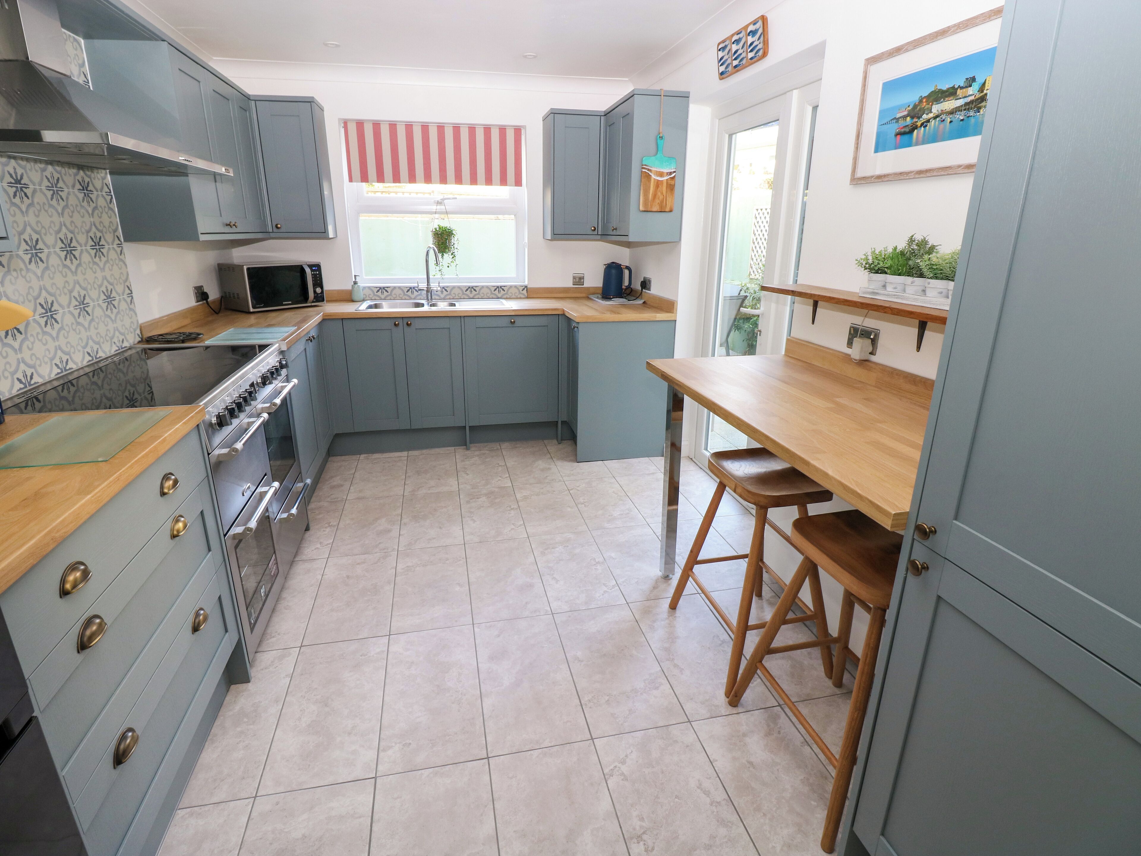 A kitchen with blue cabinets, a wooden countertop, a stove, and a sink.