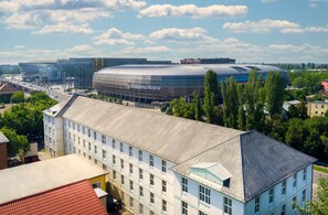 Un bâtiment moderne doté d’une grande façade en verre et d’une structure en forme de dôme remarquable, portant l’inscription « Groupama Arena ».