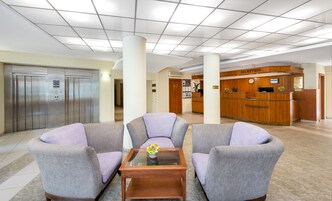 A hotel lobby with a reception desk, a reception area, and a seating area with armchairs and a coffee table.