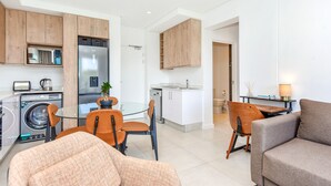 A modern apartment with a kitchen, dining area, and living room. It includes a washing machine, a refrigerator, a dining table with chairs, and a sofa. - Luxury 2 Bed in Sandton Gate (Johannesburg)