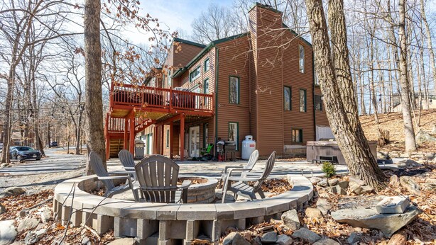 A wooden building with a balcony, outdoor seating, and a fire pit.