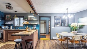 A modern kitchen with a central island, bar stools, and a dining area with a table and chairs. - Water Front Dream | Hot Tub | Fire Pit | King Bed | Community Pool | Basketball (Tobyhanna)