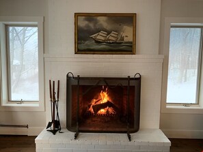 Cozy room with a warm fireplace and a beautiful painting above, offering a peaceful atmosphere.