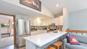 A modern kitchen with white cabinets, a large island, and a stone backsplash.