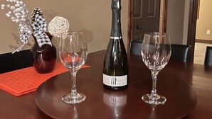 A dining table with a bottle of Van Dorp wine, two wine glasses, and decorative items. - 4-Bedroom Condo in Radium, BC (Radium Hot Springs)