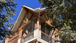 A multi-story building with a stone base, wooden beams, and balconies. - 4-Bedroom Condo in Radium, BC (Radium Hot Springs)