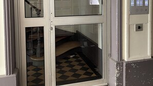 A door with a sign indicating no entry for parties, a keypad lock, and a checkered floor visible through the glass.