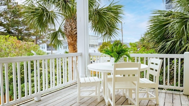 A wooden deck with a white railing, a round table with white chairs, and a potted plant. - Pie Seas - 4 bedroom with elevator, dog friendly! (Carolina Beach)