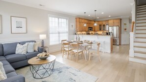 A modern living room with a sofa, coffee table, and dining area. - Pie Seas - 4 bedroom with elevator, dog friendly! (Carolina Beach)