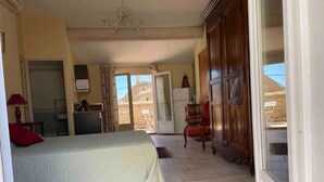 Ein Schlafzimmer mit Bett, Schreibtisch und Stuhl. Eine Schiebetür führt zu einem Balkon.