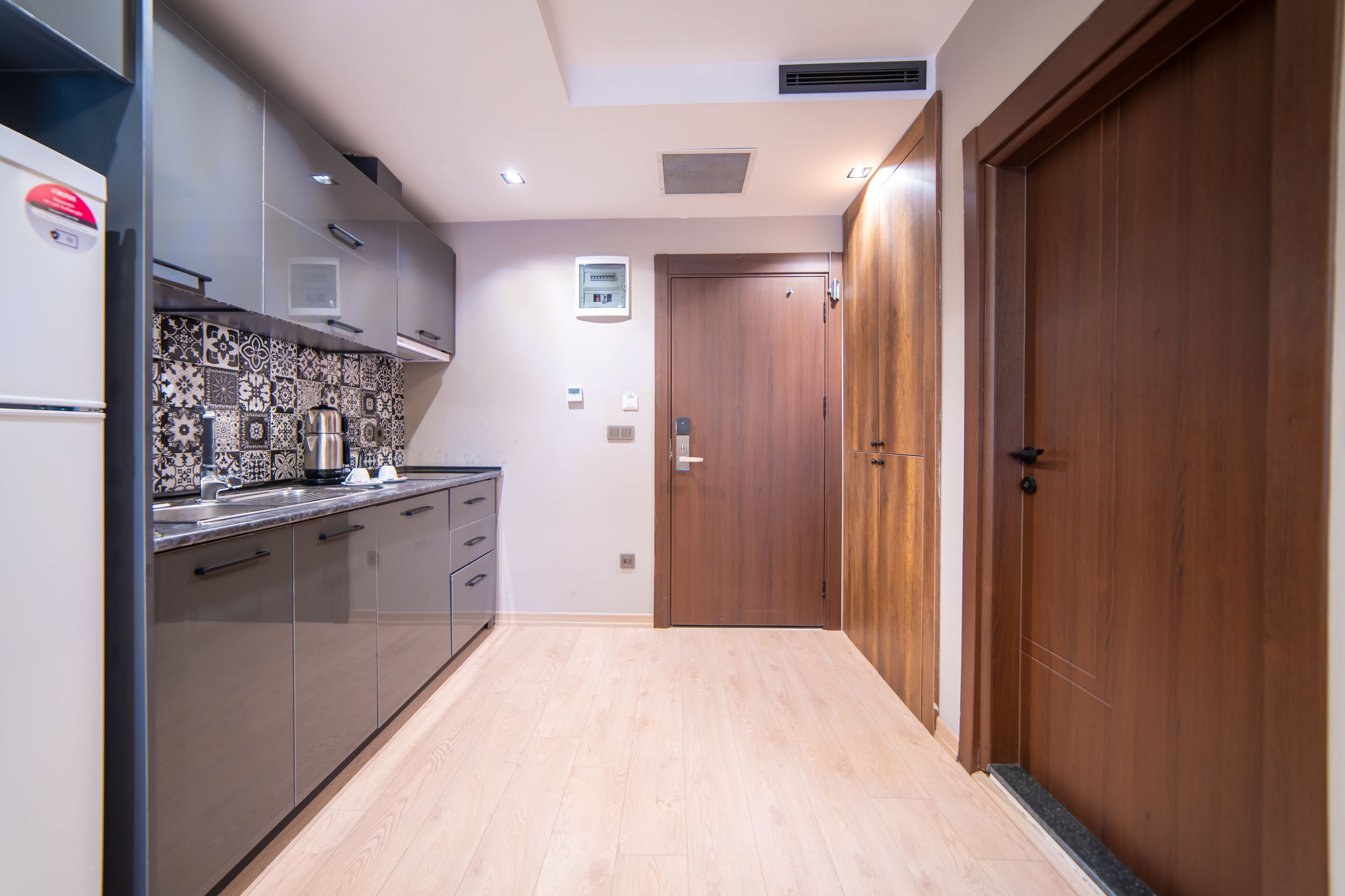 A modern kitchen with a wooden door, a built-in oven, and a tiled backsplash.