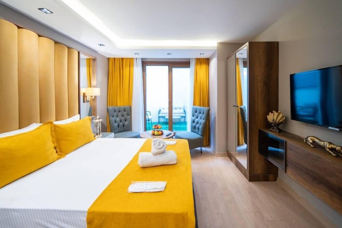 A hotel room with a bed, a desk, a chair, a TV, and a balcony view.