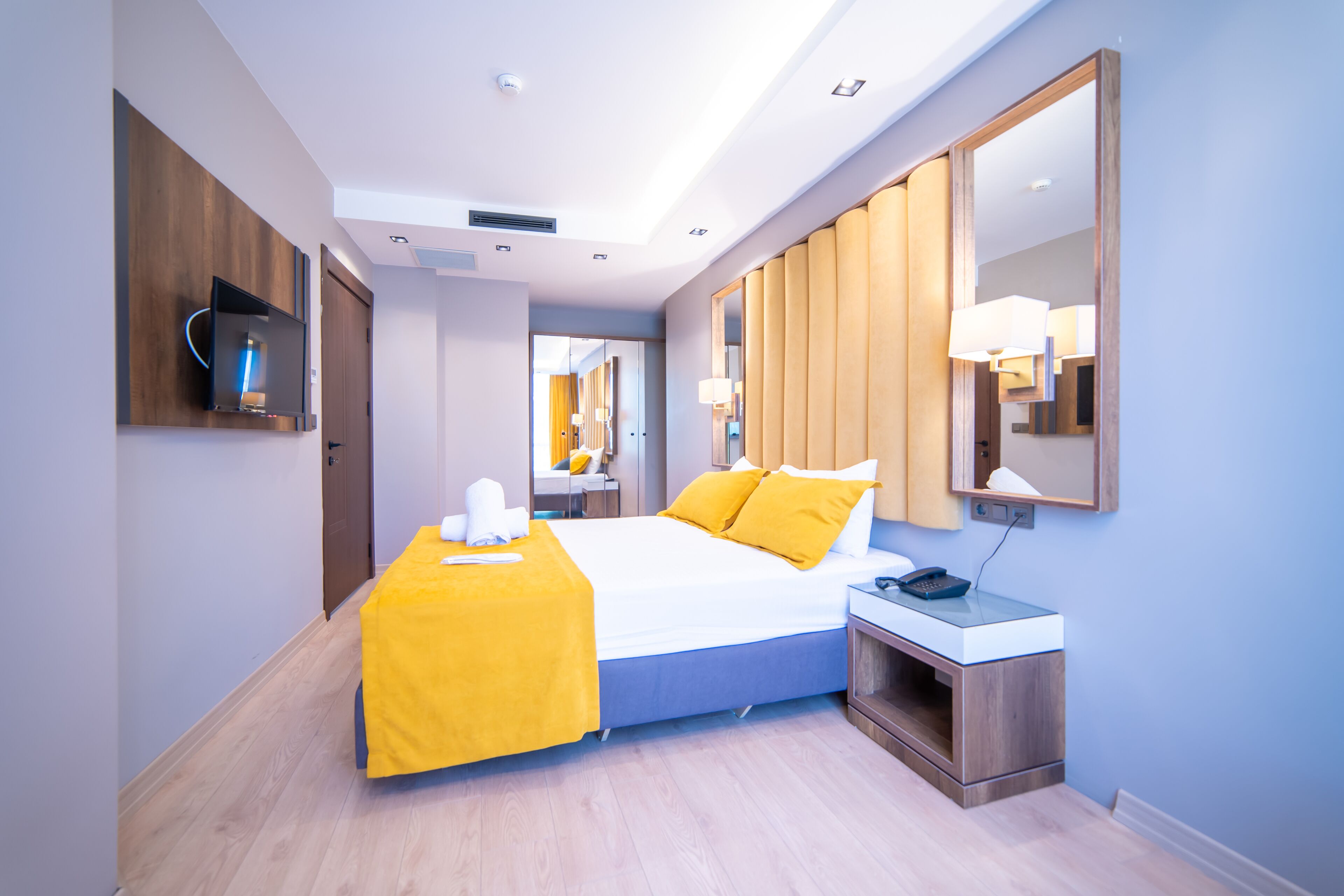 Una habitación de hotel moderna con una cama grande, una mesita de noche y un espejo.