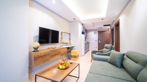 Uma sala de estar moderna com televisão de tela plana, console de madeira e sofá verde.