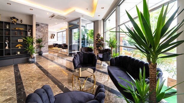 Um hall moderno com piso de mármore, sofás pretos e divisória de vidro.