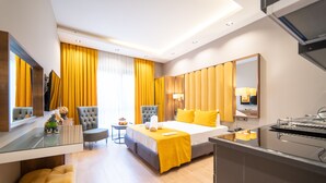 Quarto de hotel moderno com uma cama grande, uma mesa de trabalho, uma cadeira e uma mesinha.
