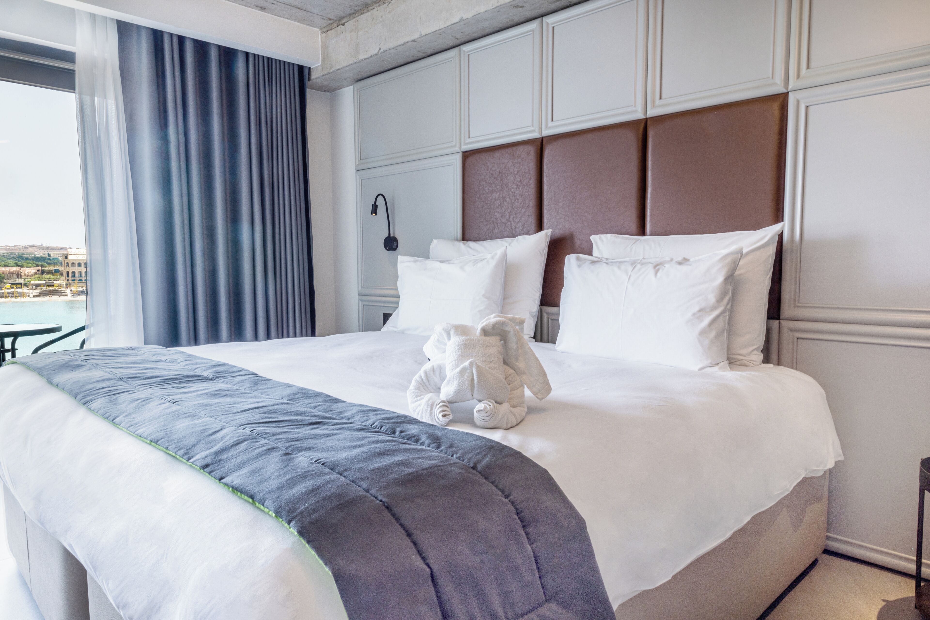 Habitación de hotel con una cama grande, vistas de la ciudad y cortinas.