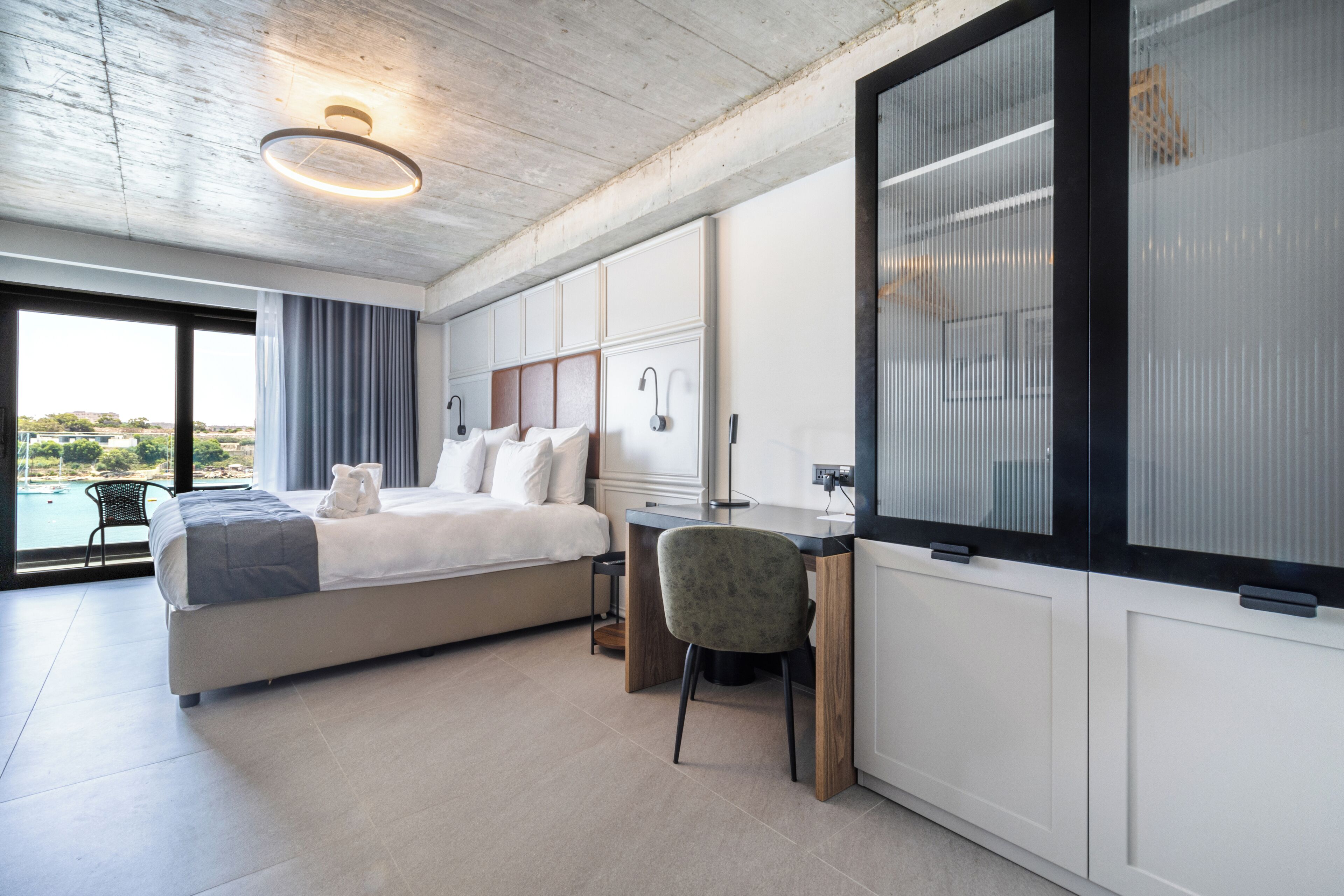 Un dormitorio moderno con una cama grande, un escritorio y vistas a una piscina.