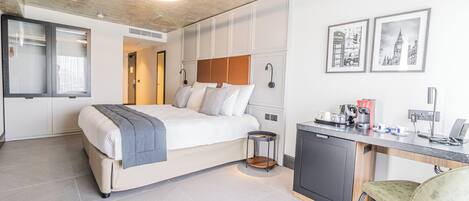 Een moderne hotelkamer met een bed, bureau, stoel en kunstwerk aan de muur.