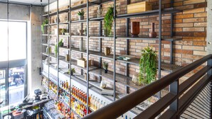 Une étagère à plusieurs niveaux, sur laquelle sont disposés divers objets et plantes, le tout adossé à un mur de briques.