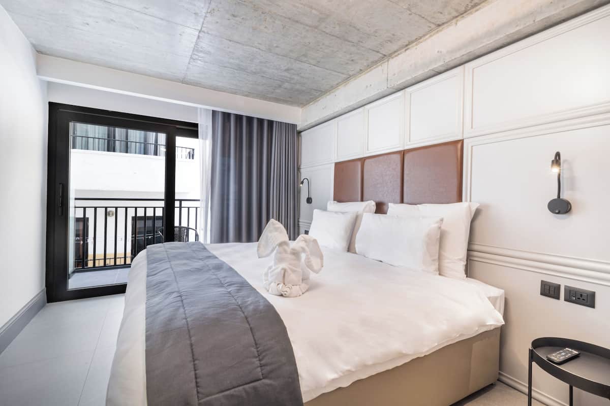 Una habitación de hotel con una cama grande, un balcón con vistas y un diseño moderno.