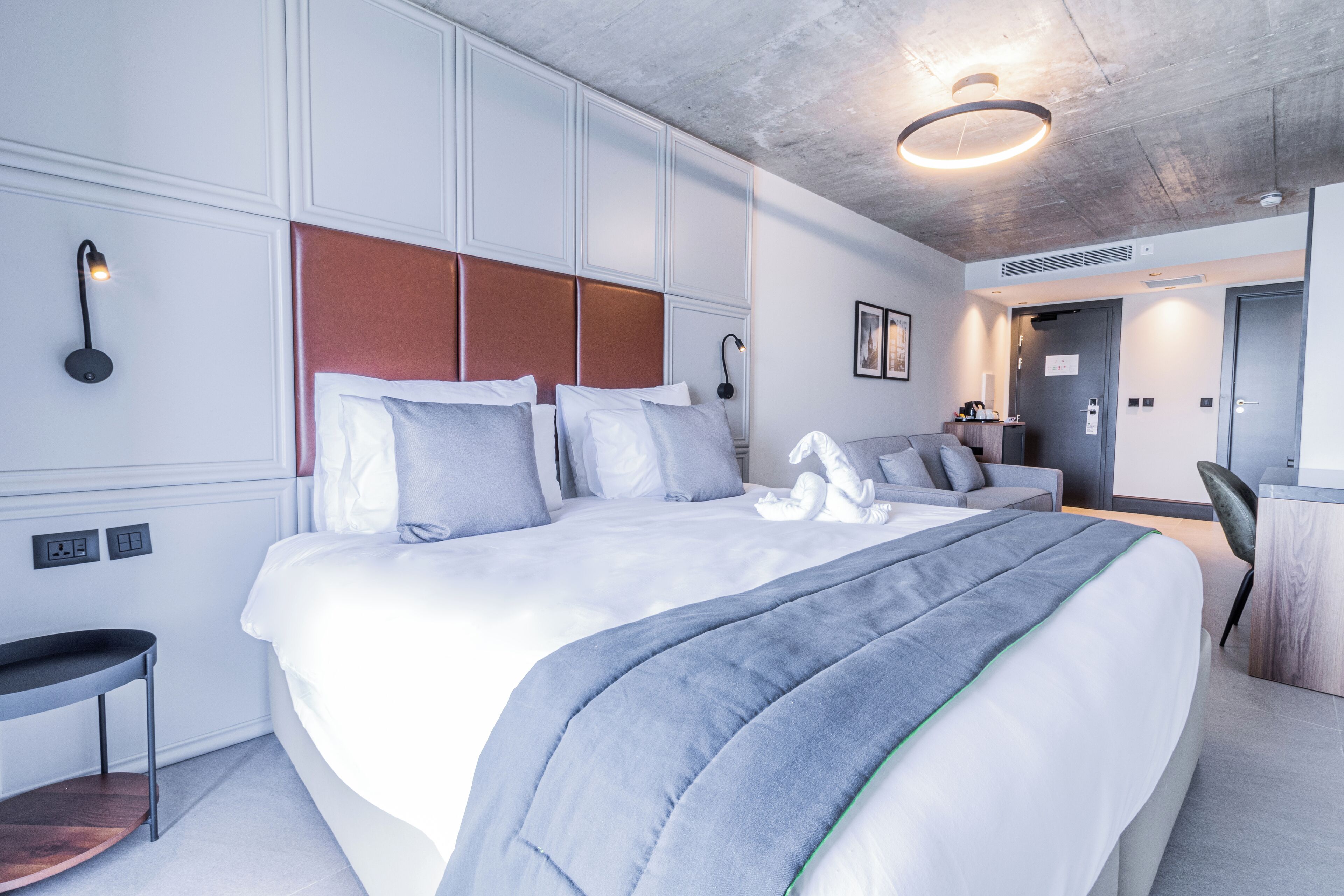 Una habitación de hotel moderna con una cama grande, un escritorio y una silla.
