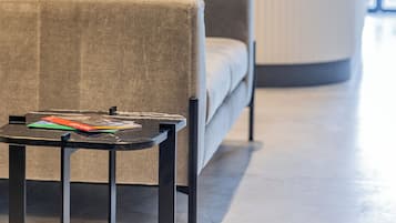 Un moderno vestíbulo de hotel con un sofá, una mesita con un libro y un mostrador de recepción.