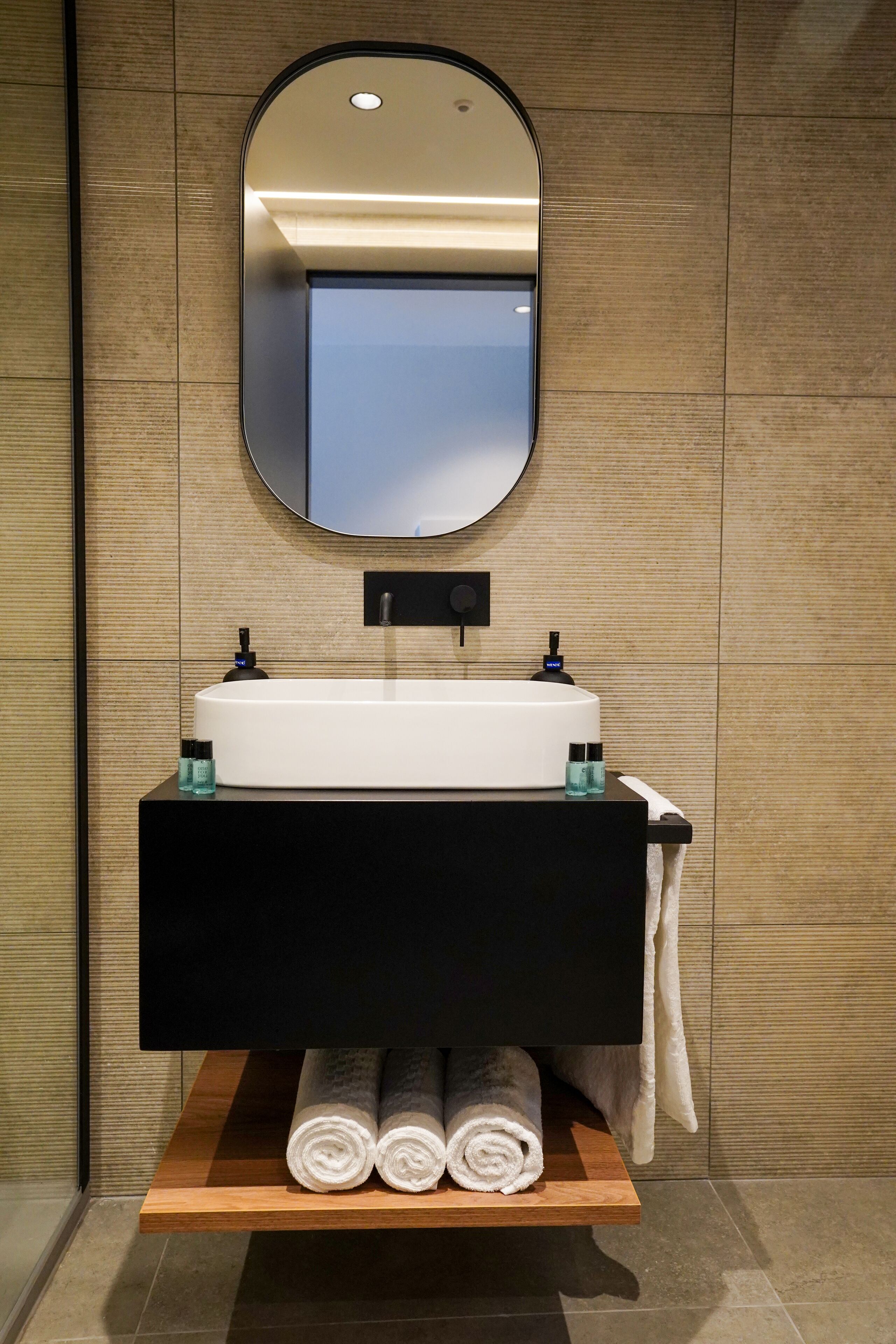 Une salle de bain moderne avec un lavabo blanc, un meuble-lavabo noir et un miroir au-dessus.
