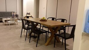 A dining area with a wooden table and black chairs, a grey sofa, and a small white table with a glass top.