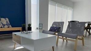 A modern office space with a white desk, two grey chairs, a blue wall, and a window with blinds.