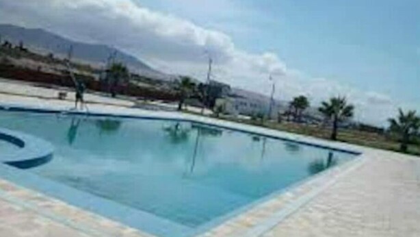 A swimming pool with a clear view of the surrounding landscape, including mountains and palm trees.