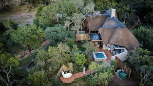 An aerial view of a thatched-roof house surrounded by dense greenery, with a swimming pool and a hot tub visible. - Serondella Safari Lodge (Hoedspruit)