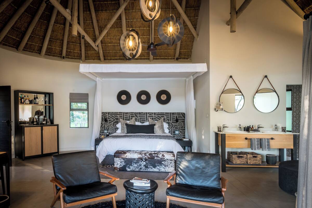 A modern bedroom with a large bed, a wooden ceiling, and a built-in desk with a mirror.