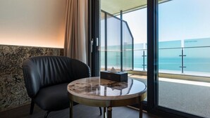 A room with a leather chair, a marble table, and a view of the sea through a glass door. - HOTEL GITE (Siheung)