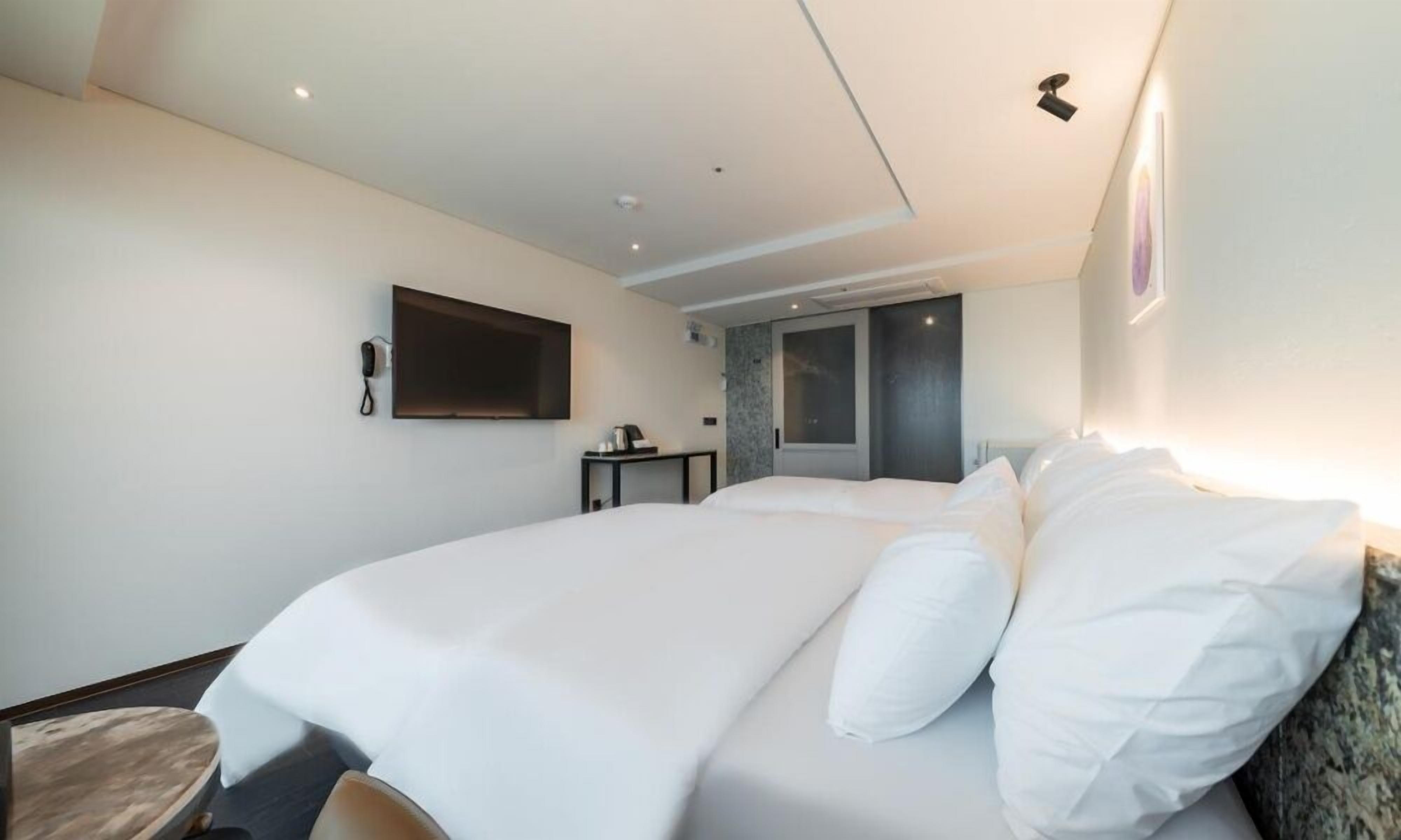 Ein Hotelzimmer mit einem großen Bett, einem Schreibtisch, einem Flachbildfernseher und einer Tür zu einem Badezimmer.