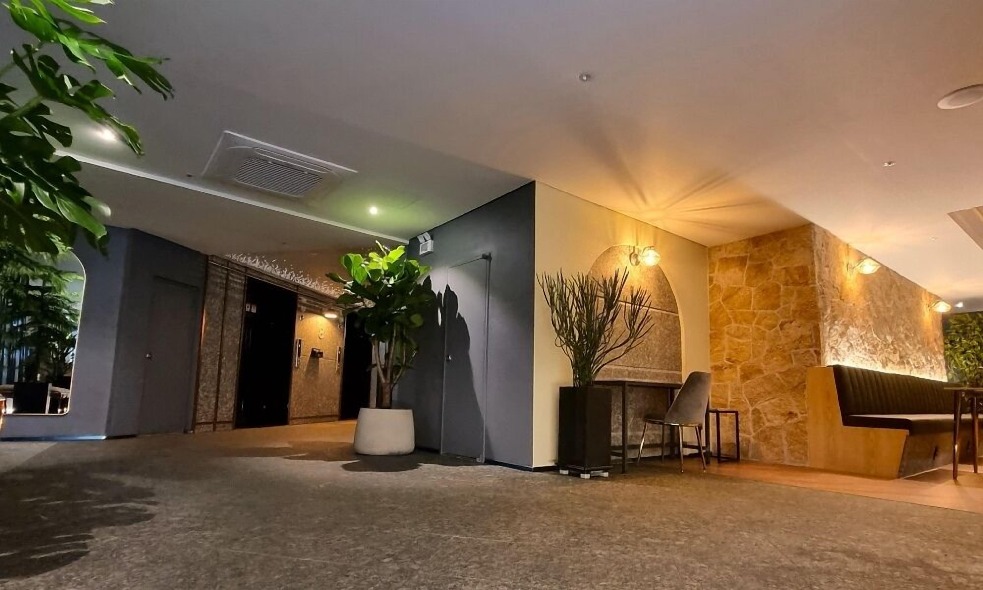 A modern lobby with a stone wall, a reception desk, and a seating area.