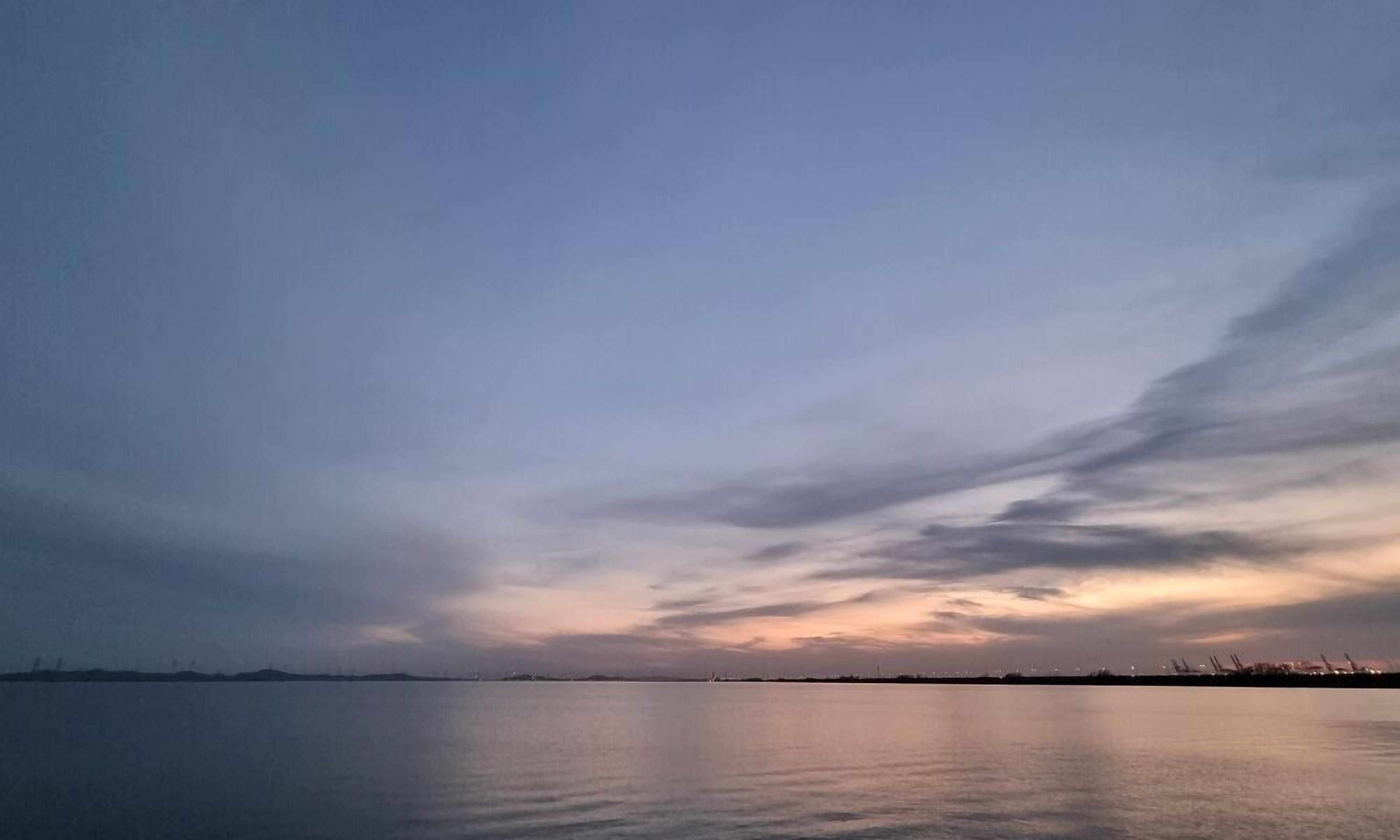 A calm body of water with a distant shoreline and a clear sky.