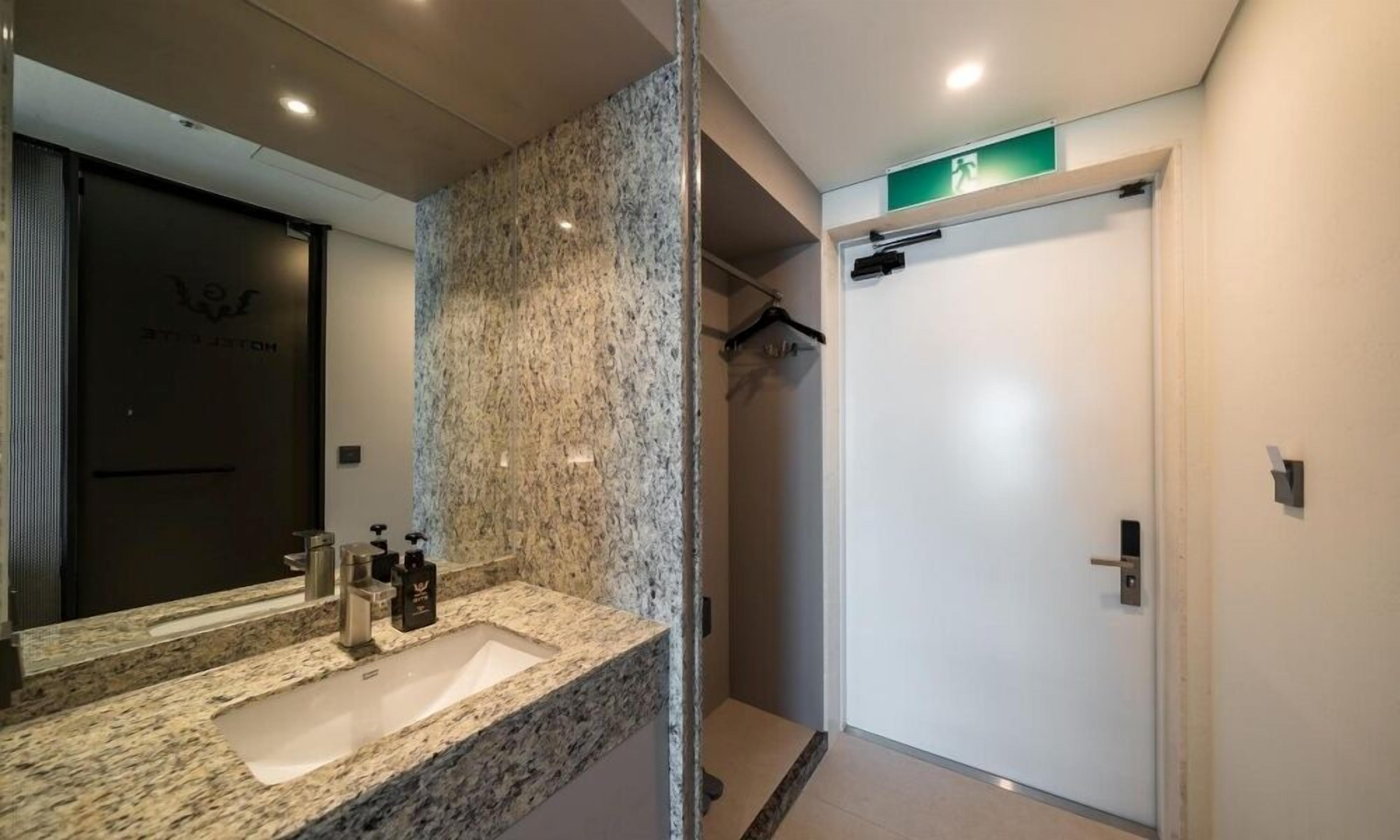 Une salle de bain moderne avec un comptoir en granit, un grand miroir et un espace douche.