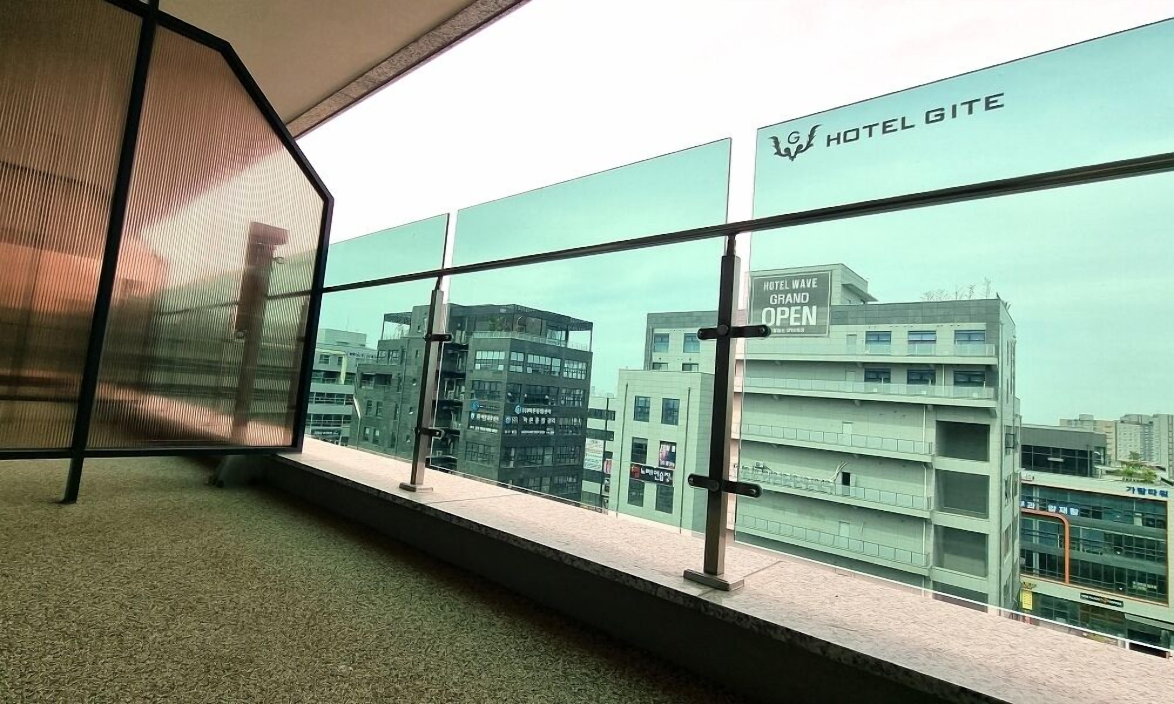 A view from a hotel room with a large window overlooking a modern building labeled "HOTEL GITE."