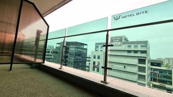 Blick aus einem Hotelzimmer mit großem Fenster auf ein modernes Gebäude, auf dem 'HOTEL GITE' steht.
