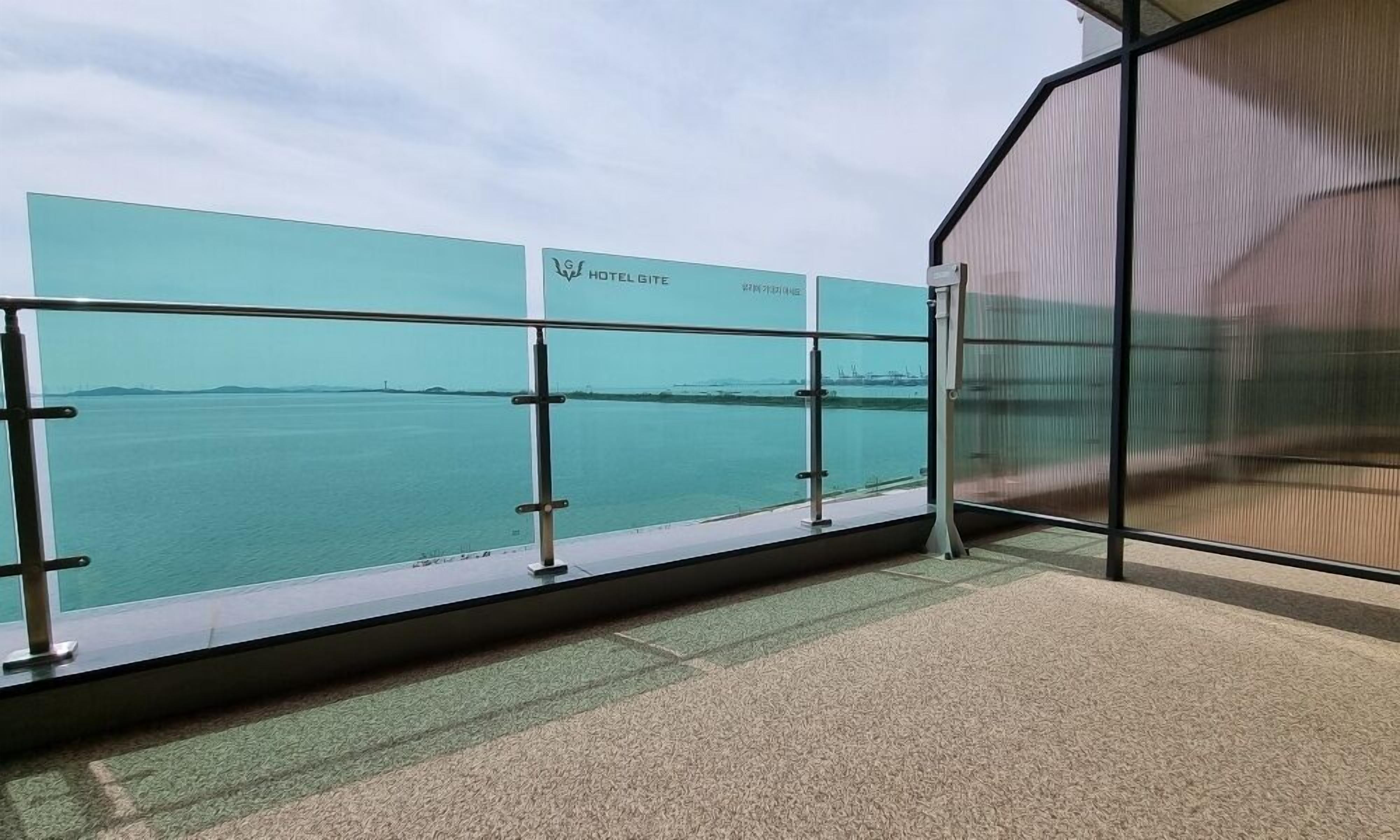 A balcony with a view of a calm body of water and distant land.
