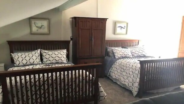 Une chambre avec deux lits, une armoire en bois et une table de chevet.